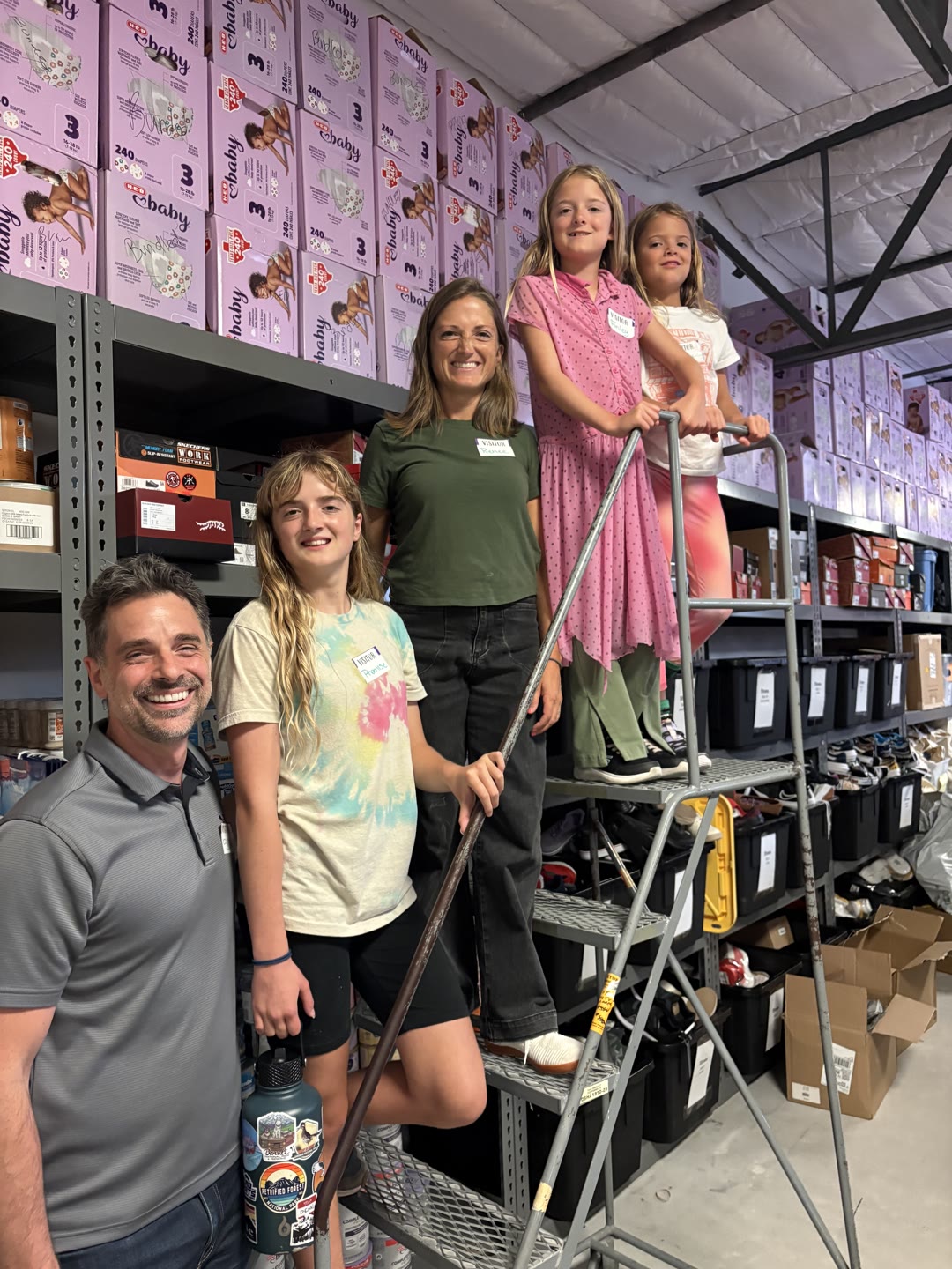 Volunteers and their families restocking shelves at the Partnerships for Children warehouse