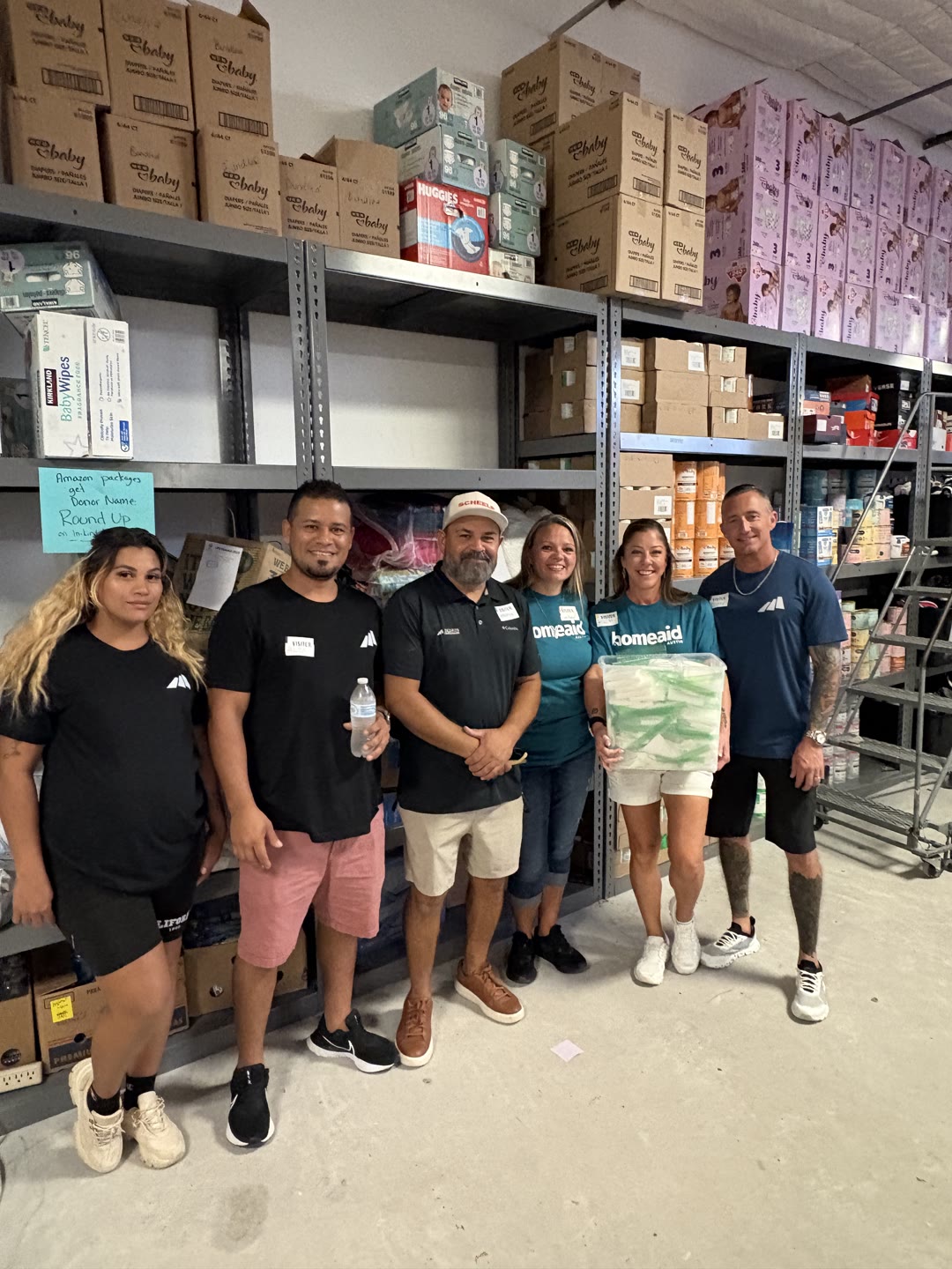 Committee Care Day volunteers together in front of the donation shelves