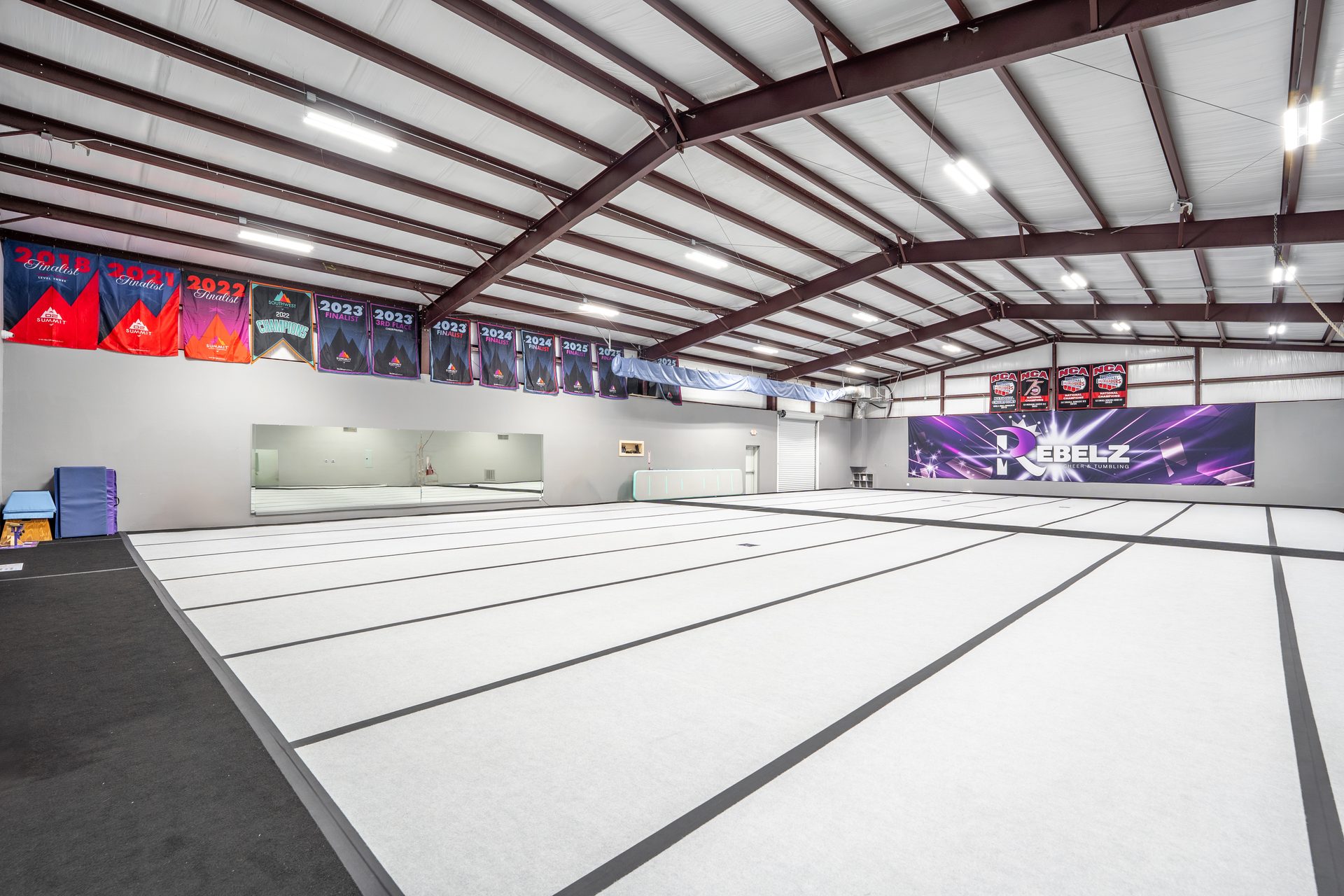 Rebelz Gym training floor with championship banners and mirror wall
