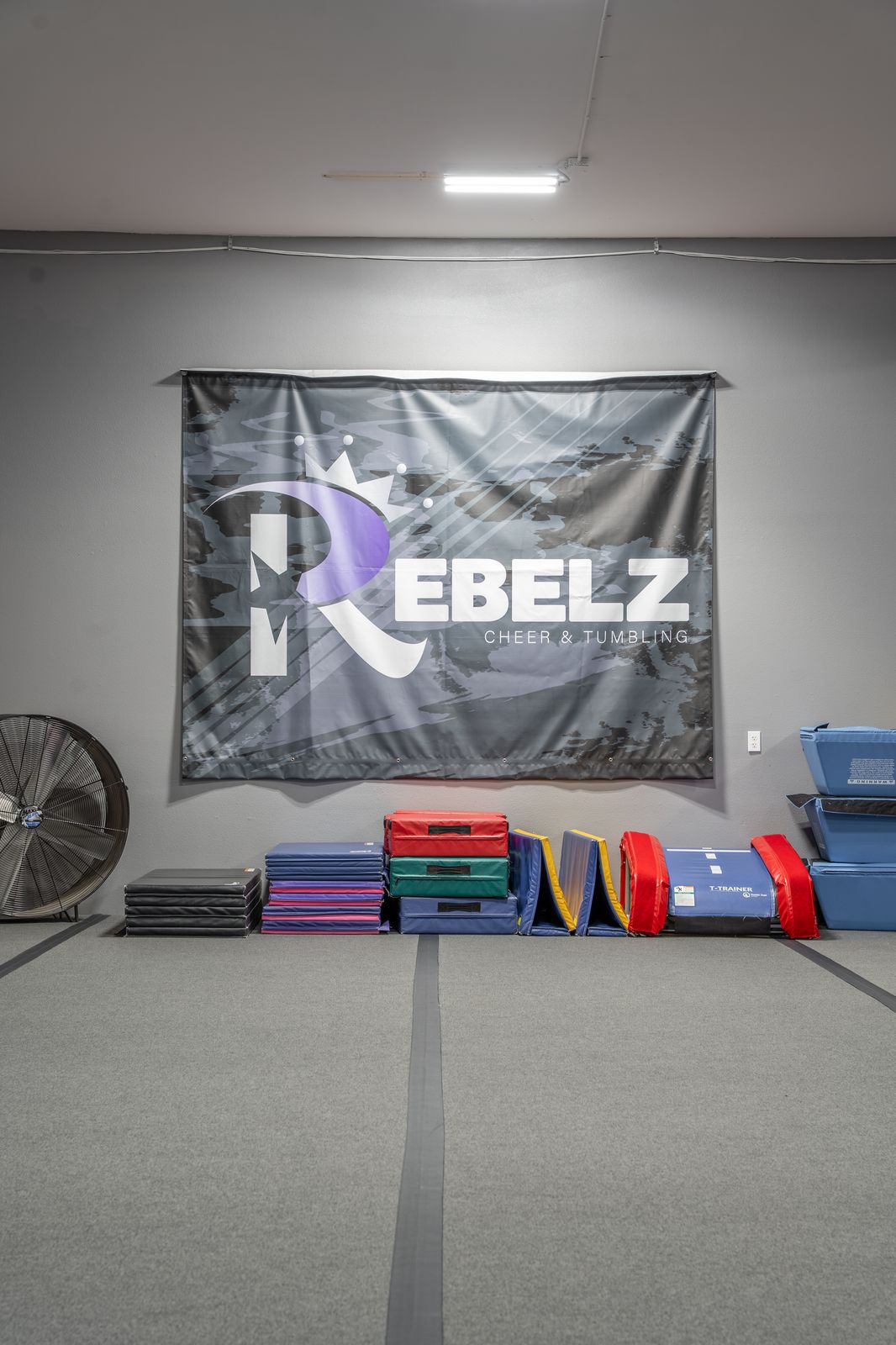 Rebelz Gym training floor with equipment storage and Rebelz banner wall