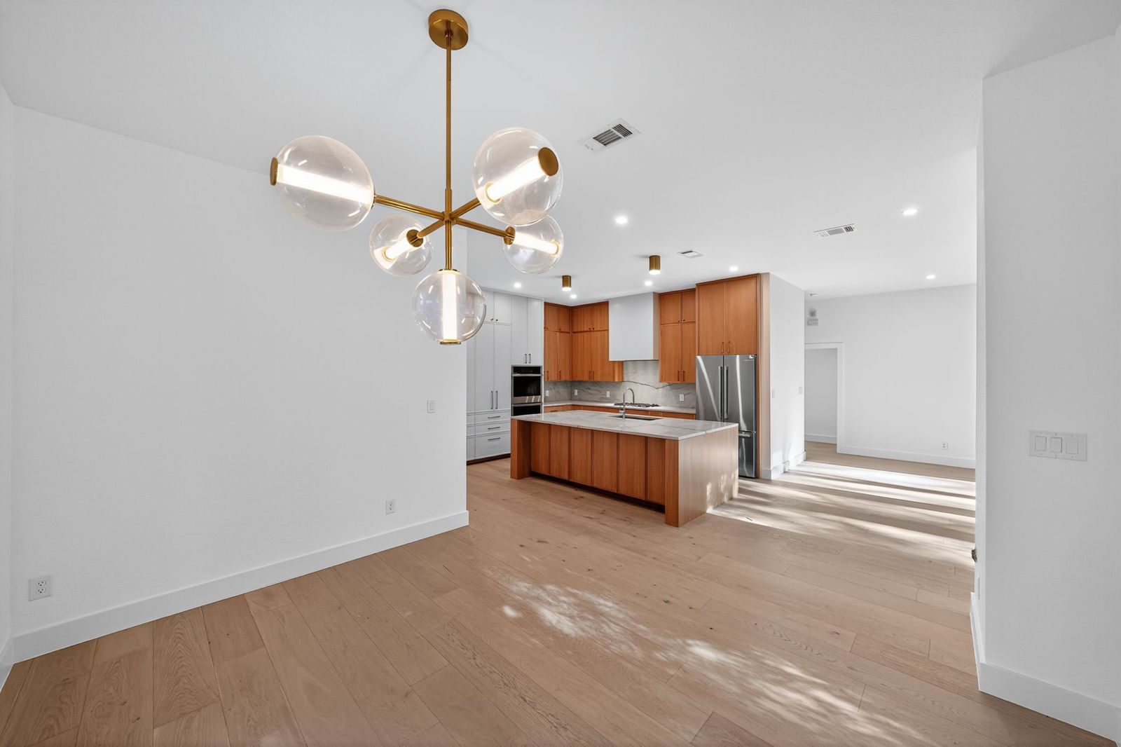 Along Creek Cove finished kitchen and dining transition with statement chandelier, Avery Ranch, Austin, TX