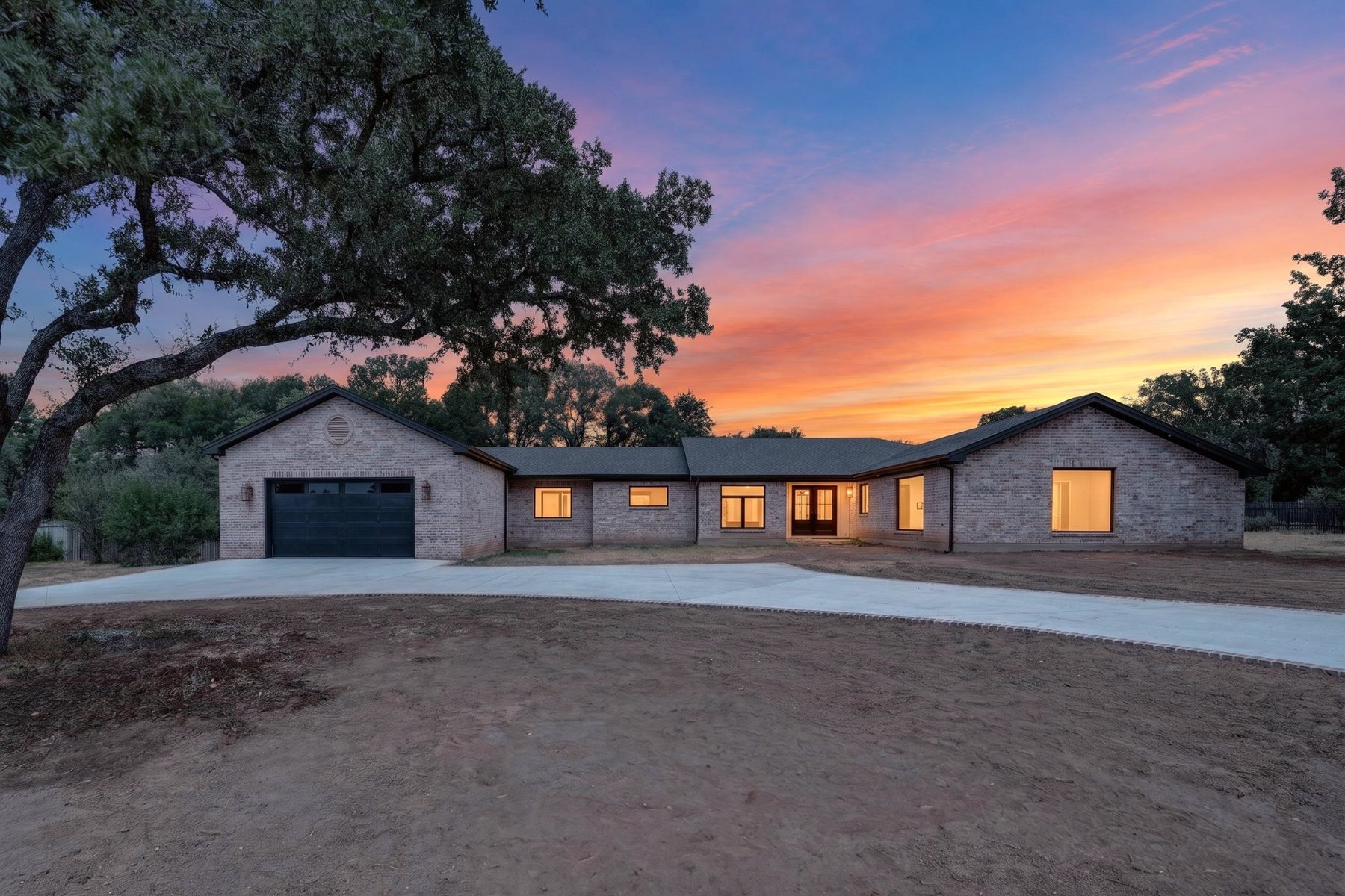 Finished North Austin home at dusk, front exterior with lit windows, North Austin, TX