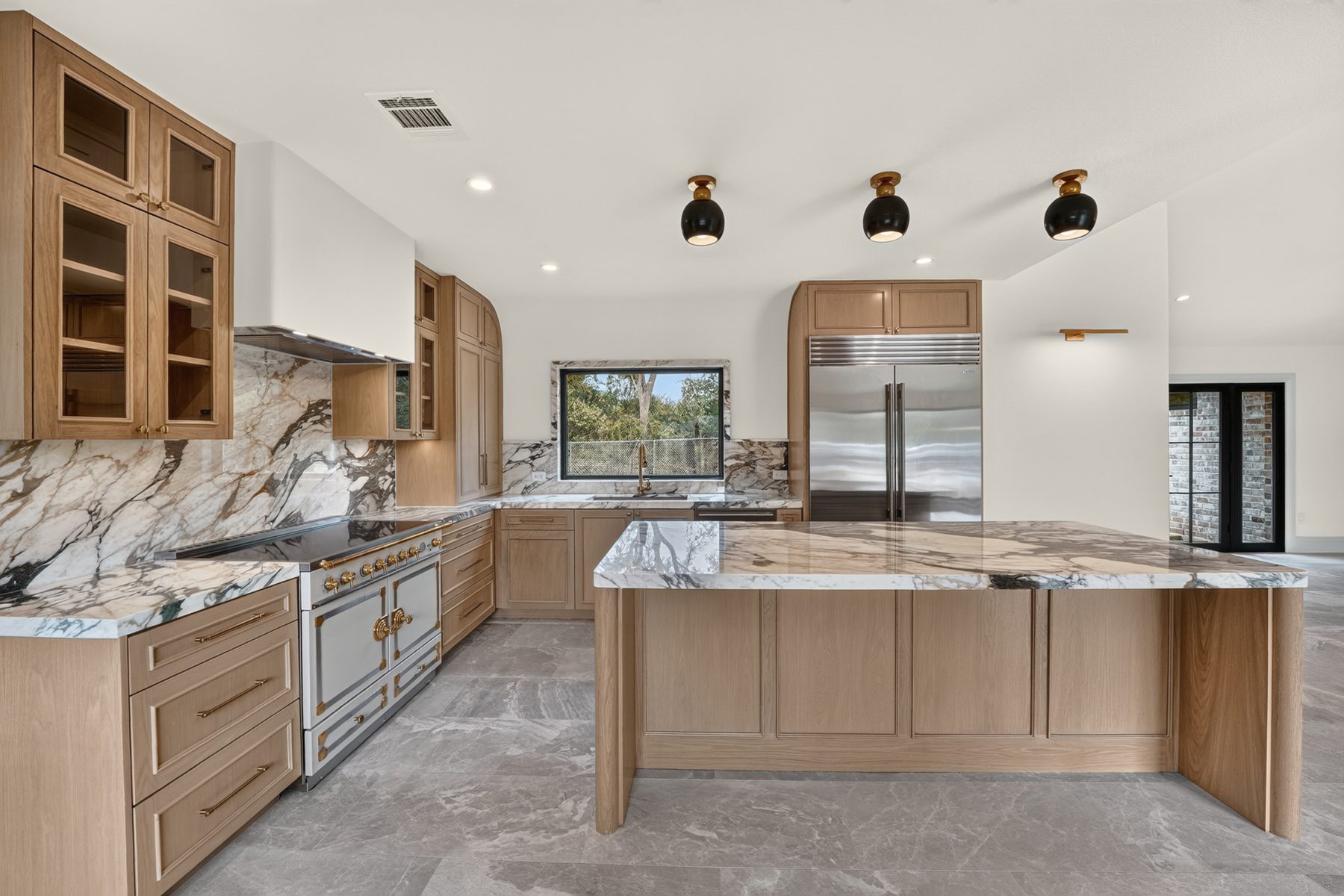 Finished kitchen with natural wood cabinetry and marble island, North Austin, TX