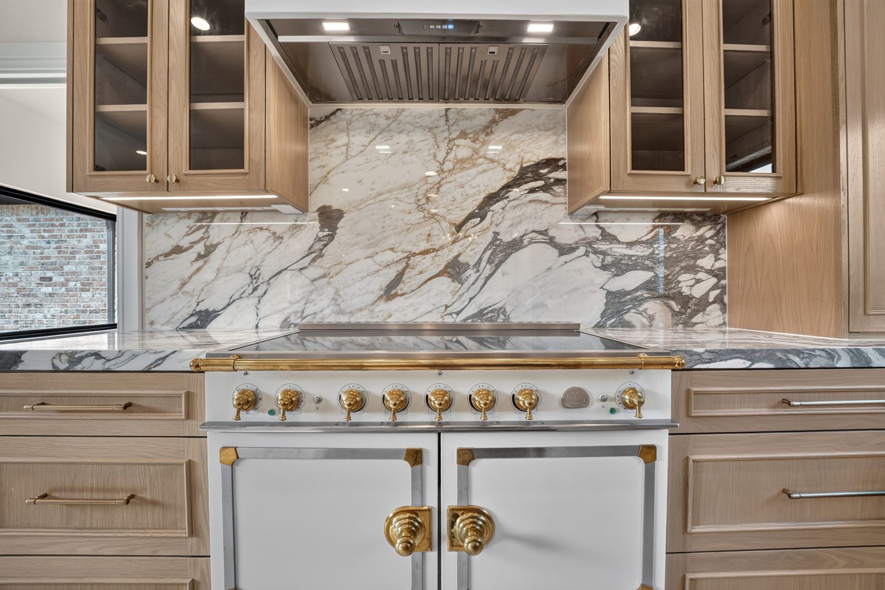 Marble backsplash and range wall with glass-front cabinets, North Austin, TX